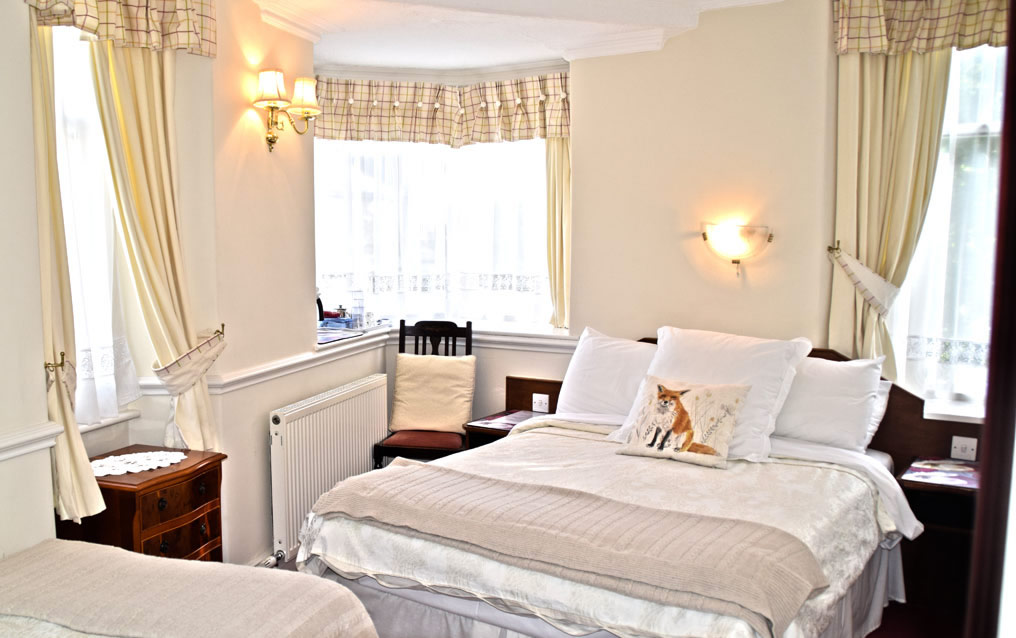 A spacious triple room with a bay window and comfortable beds for up to three guests